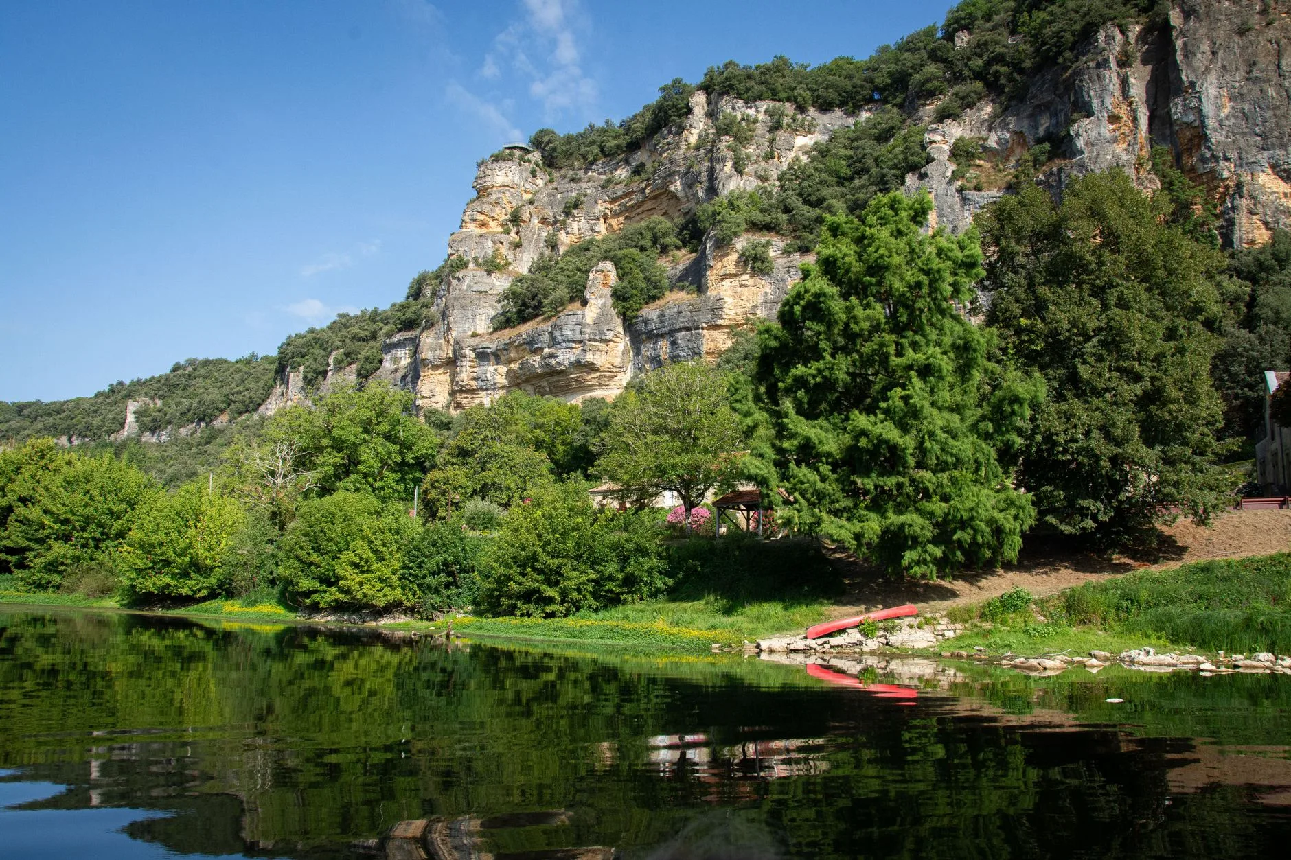 Canoës descendant la rivière Dordogne au pied de falaises et de villages de pierre